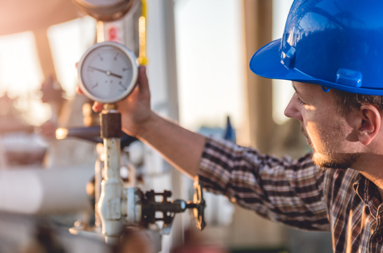 Energy and utility servies shown by a worker checking a pressure guage Energy and utility servies shown by a worker checking a pressure guage